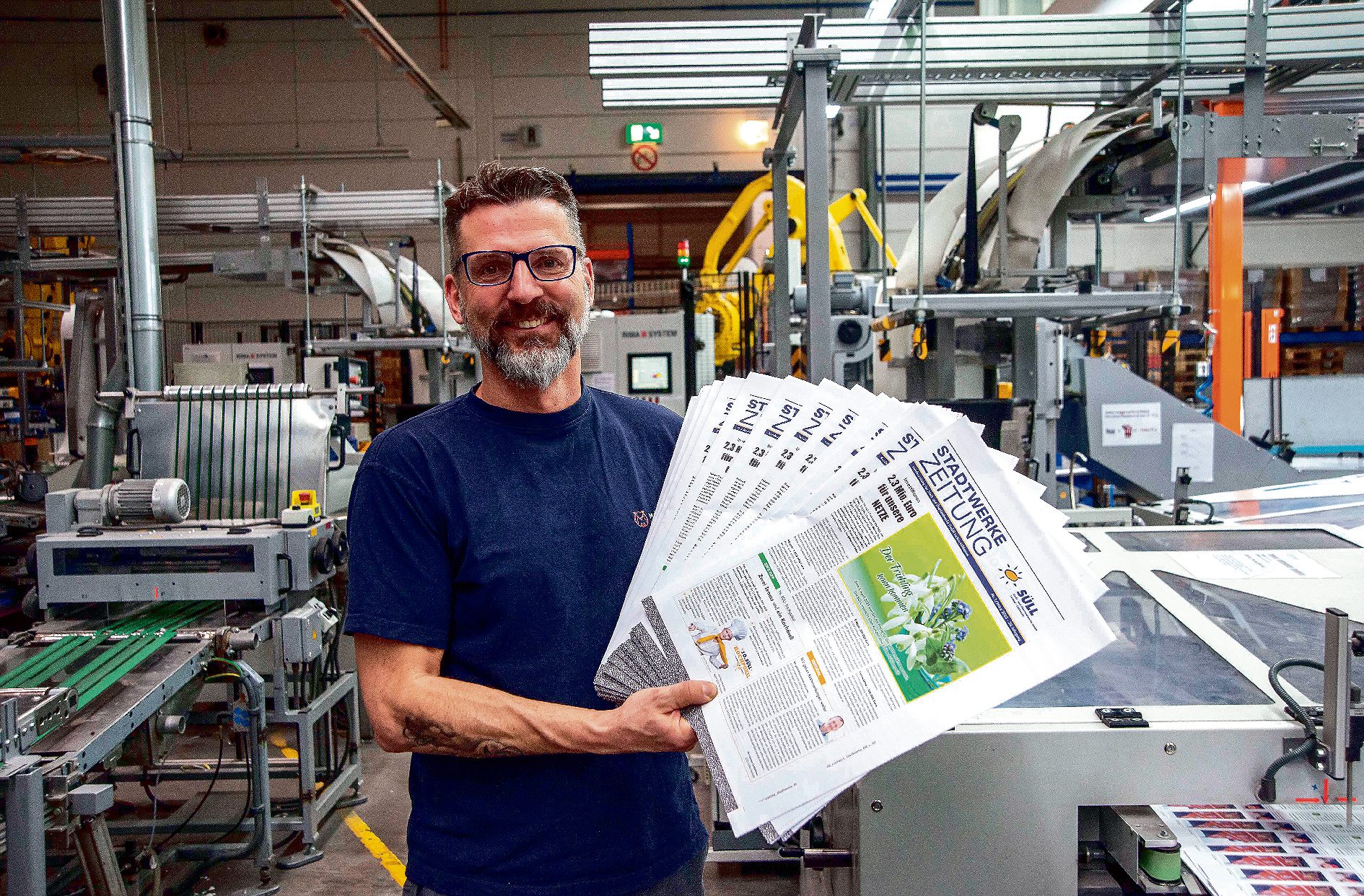 22 . 02 . 2023 , Brandenburg / Ahrensfelde : Druckerei Möller Pro Media GmbH . Foto : Druckereileiter Daniel Burisch mit frisch gedrucken Stadtwerkezeitungen.